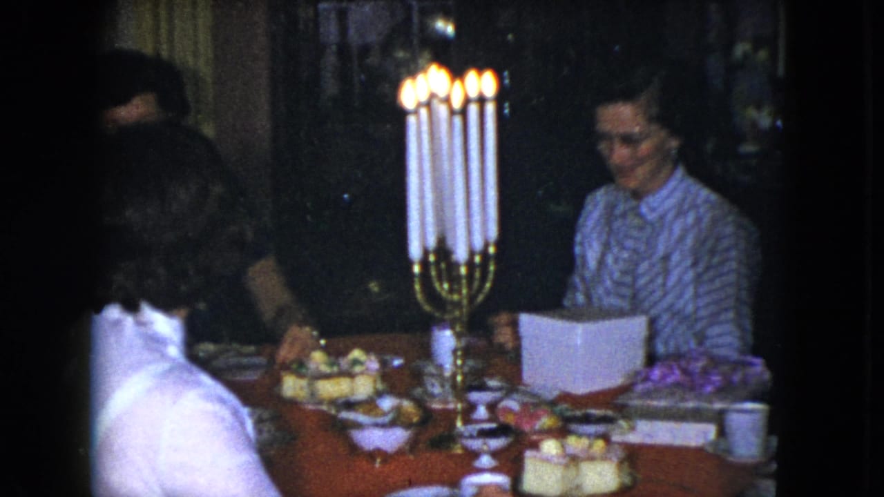 1951 Cleveland frame of a woman in a striped blouse seated at a candlelit dinner table in a private interior.