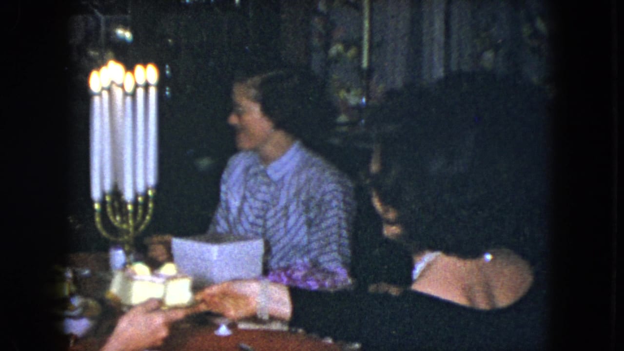 In Cleveland 1951 home-movie footage, two adult women sit beside a tall lit candelabra at a dining table.