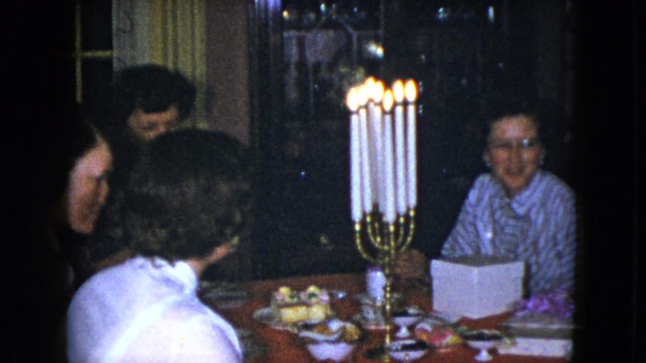 Cleveland, Ohio 1951 frame of women in conversation around a dining table lit by a tall brass candelabra.