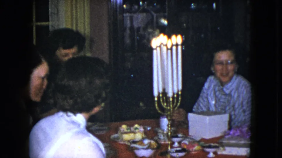 Cleveland, Ohio 1951 frame of women in conversation around a dining table lit by a tall brass candelabra.