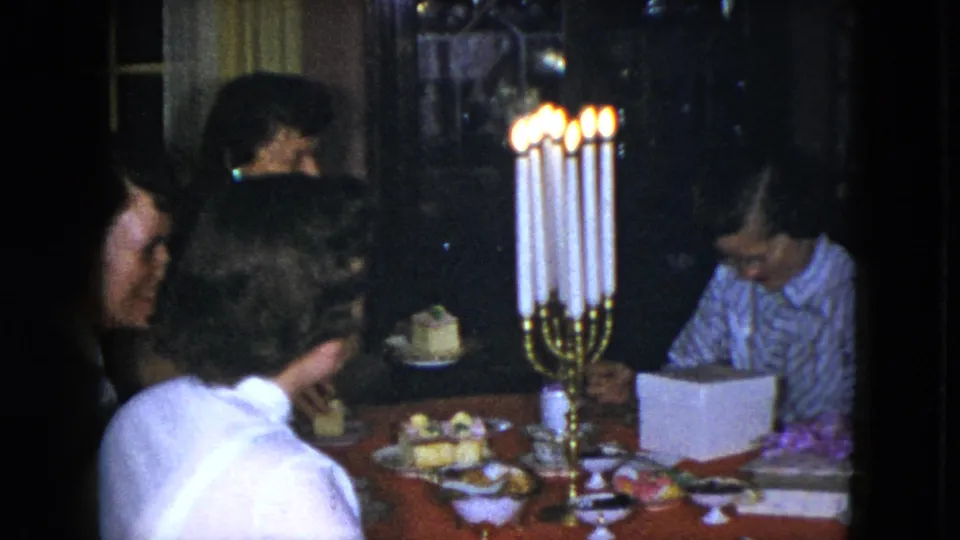 Cleveland, Ohio 1951 home-movie frame of women leaning around a candlelit dining table in a private interior.