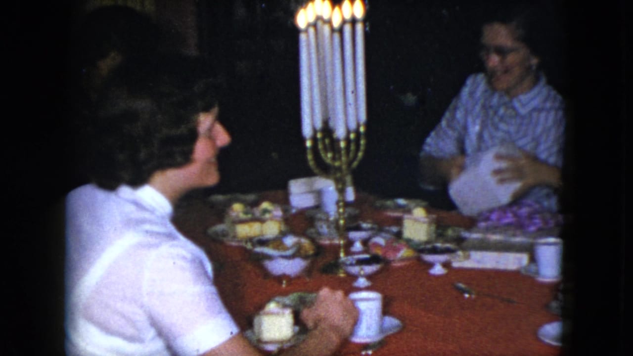 Cleveland 1951 interior dinner scene with a woman handling paper or packaging beside lit candles and dessert plates.