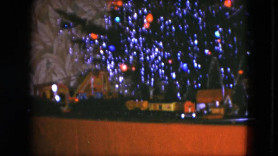 A closer 1951 Cleveland frame shows the lit Christmas tree above model houses and a toy railway display.