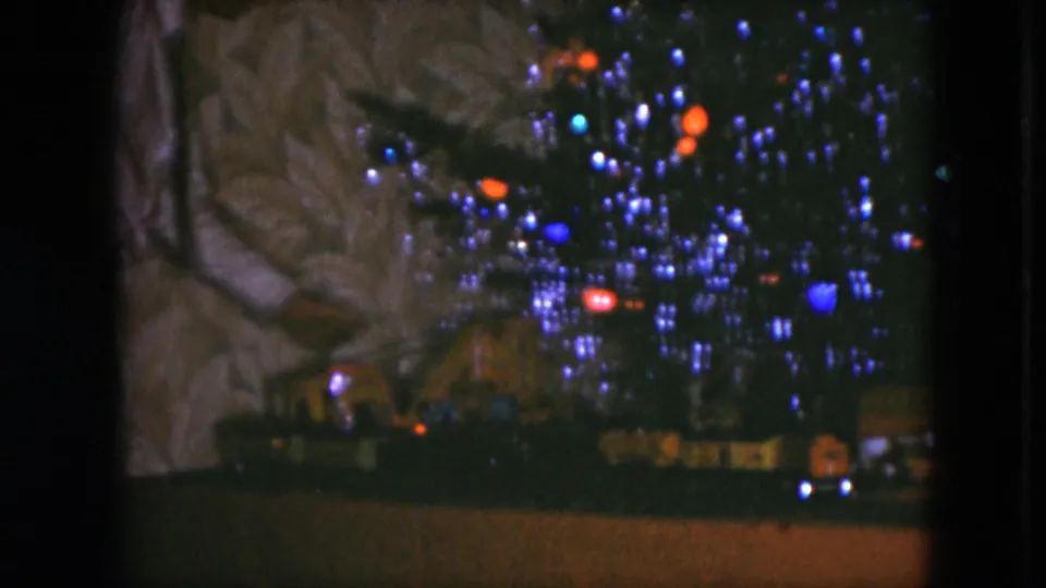 1951 Cleveland home-movie frame showing a Christmas tree with blue and red lights above a toy train display.