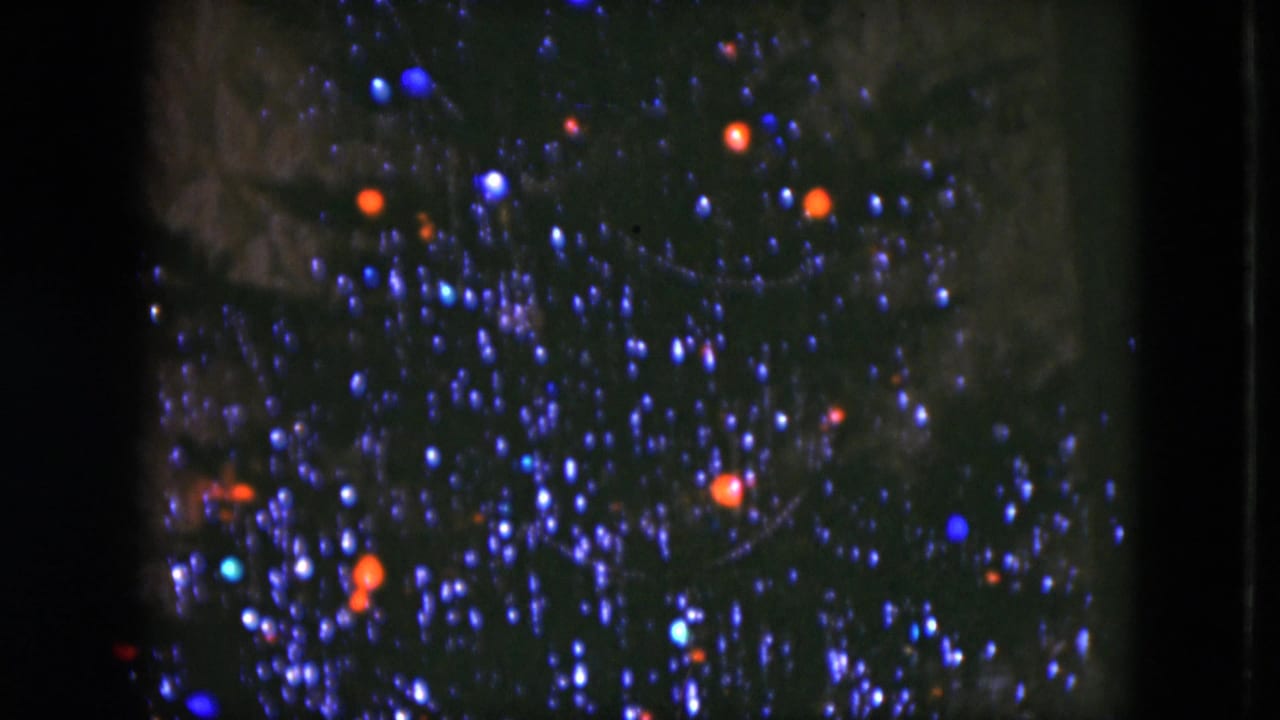 1951 Cleveland 8mm frame of a decorated Christmas tree, with blue-white tinsel sparkle and scattered red and blue bulbs.