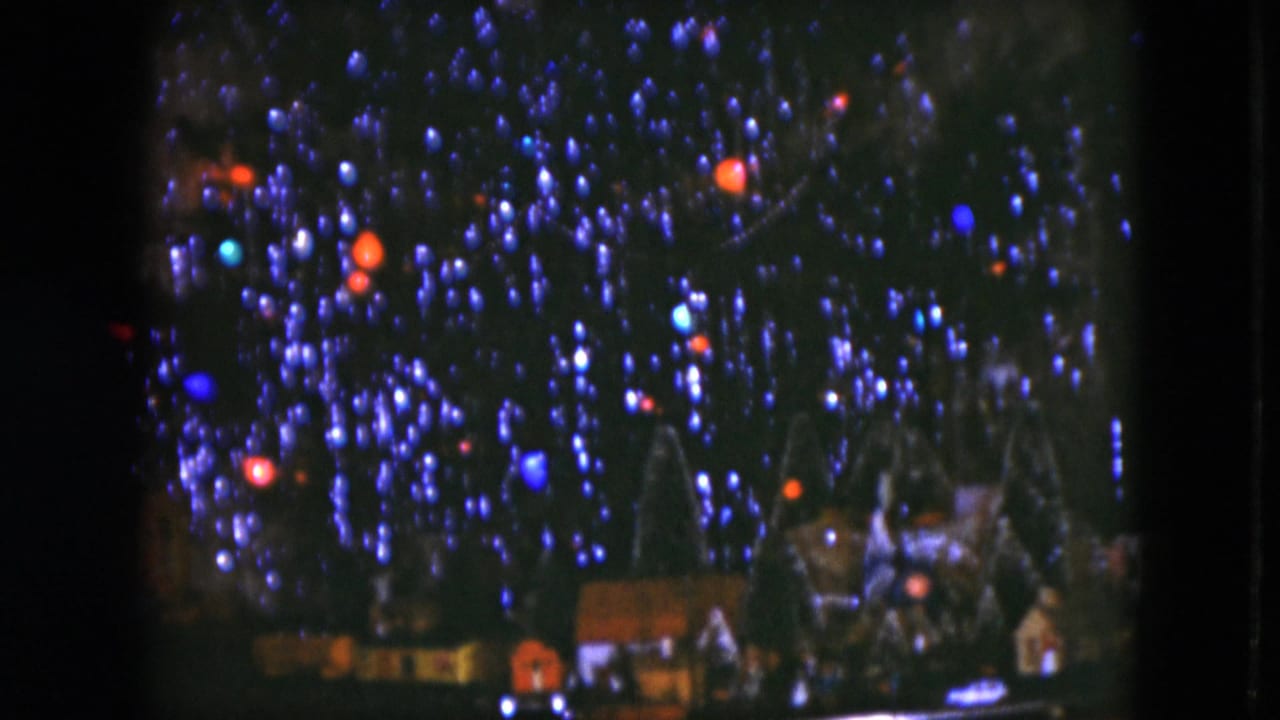 1951 Cleveland 8mm frame of glowing Christmas bulbs with a miniature holiday village and train-set scenery at the tree base.