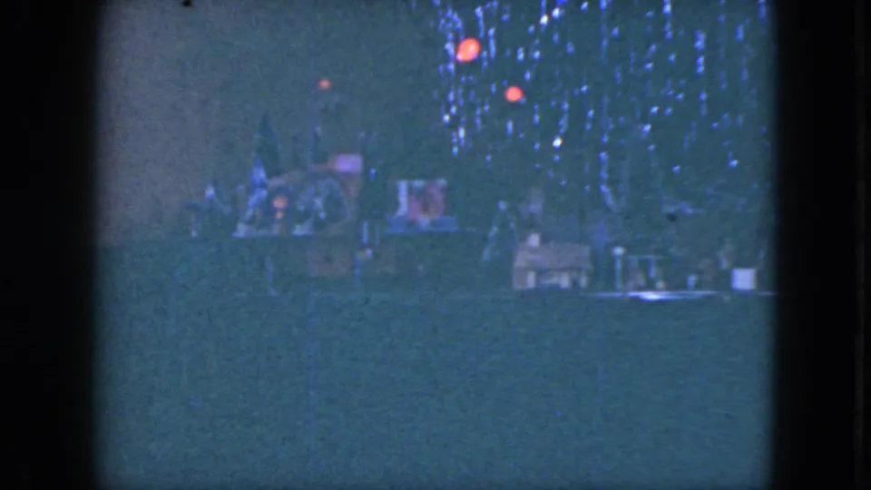 1951 Cleveland home-movie frame with a decorated Christmas tree behind a miniature railroad arrangement.