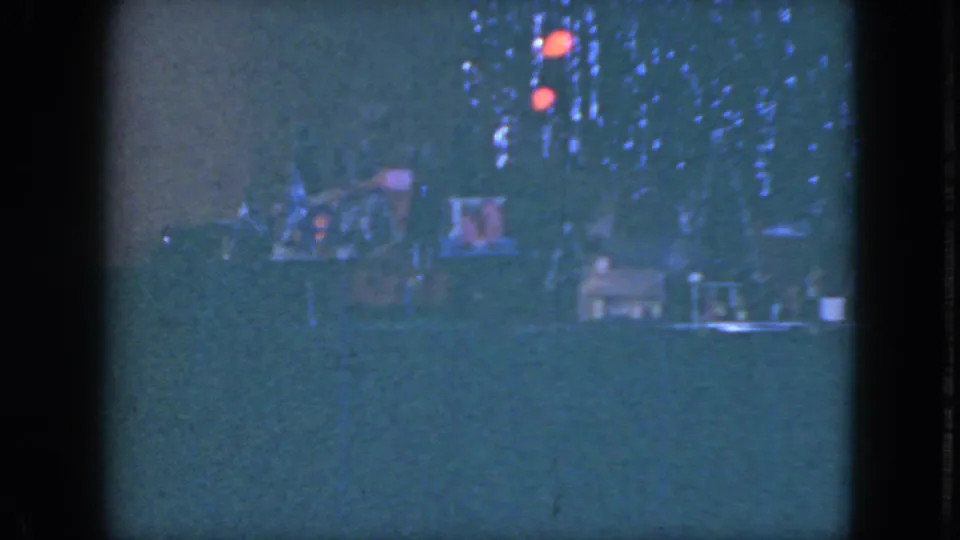 Blue, grainy 8mm frame from the 1951 Cleveland holiday clip showing tree lights and a miniature train layout.