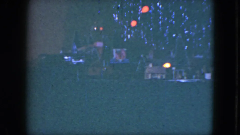 1951 Cleveland home-movie frame showing a model train and glowing tree lights beneath a Christmas tree.