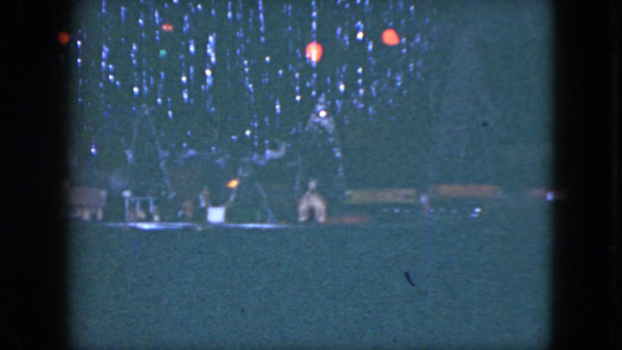 The Cleveland 1951 footage holds on a dim miniature train setup with small houses, trees, and red hanging lights.