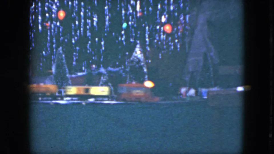 The lit model train passes through the 1951 Cleveland holiday display, with miniature houses and trees behind it.