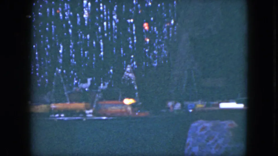 1951 Cleveland home-movie frame showing a model train display below a decorated Christmas tree with red and blue lights.