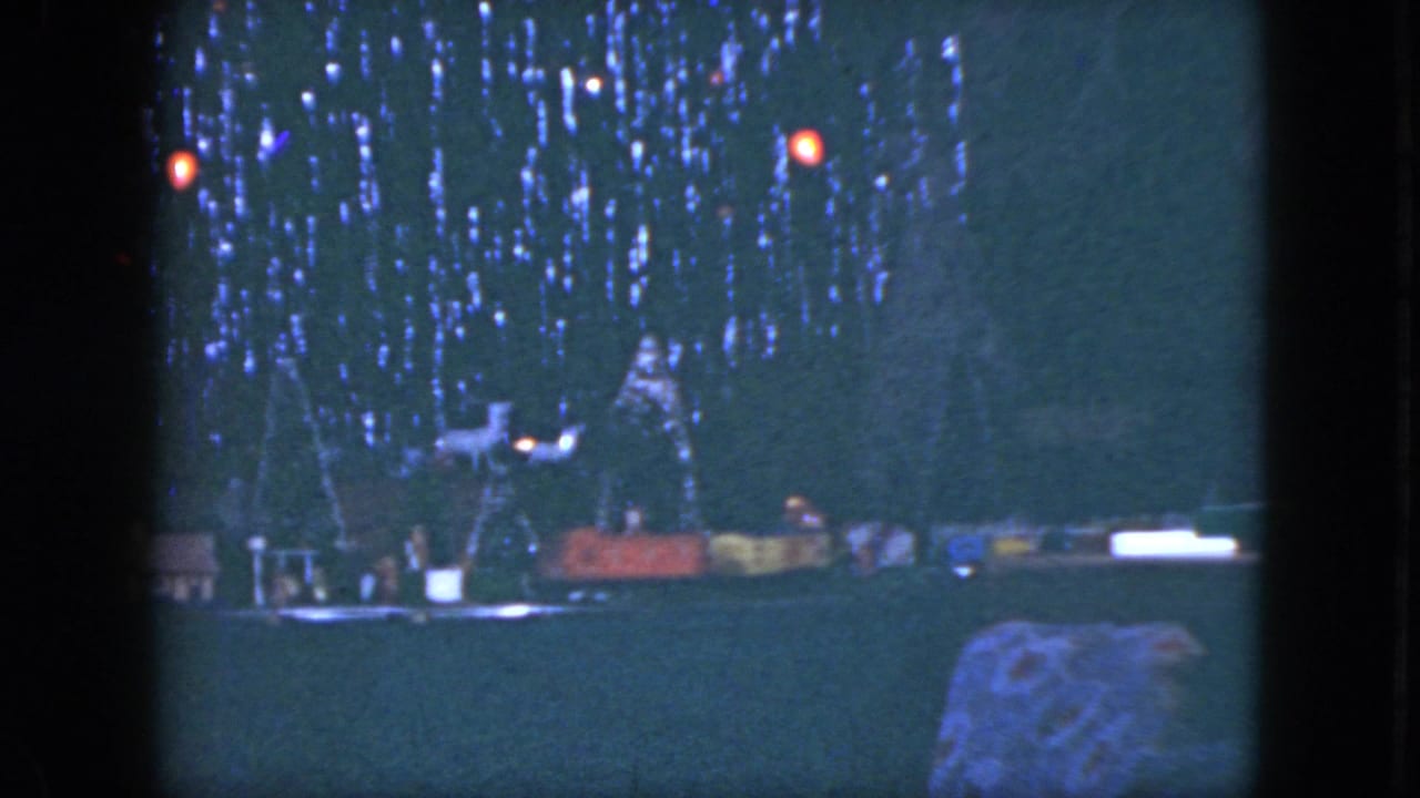 1951 Cleveland frame with a dark Christmas tree, colored lights, and small train-set scenery along the lower edge.