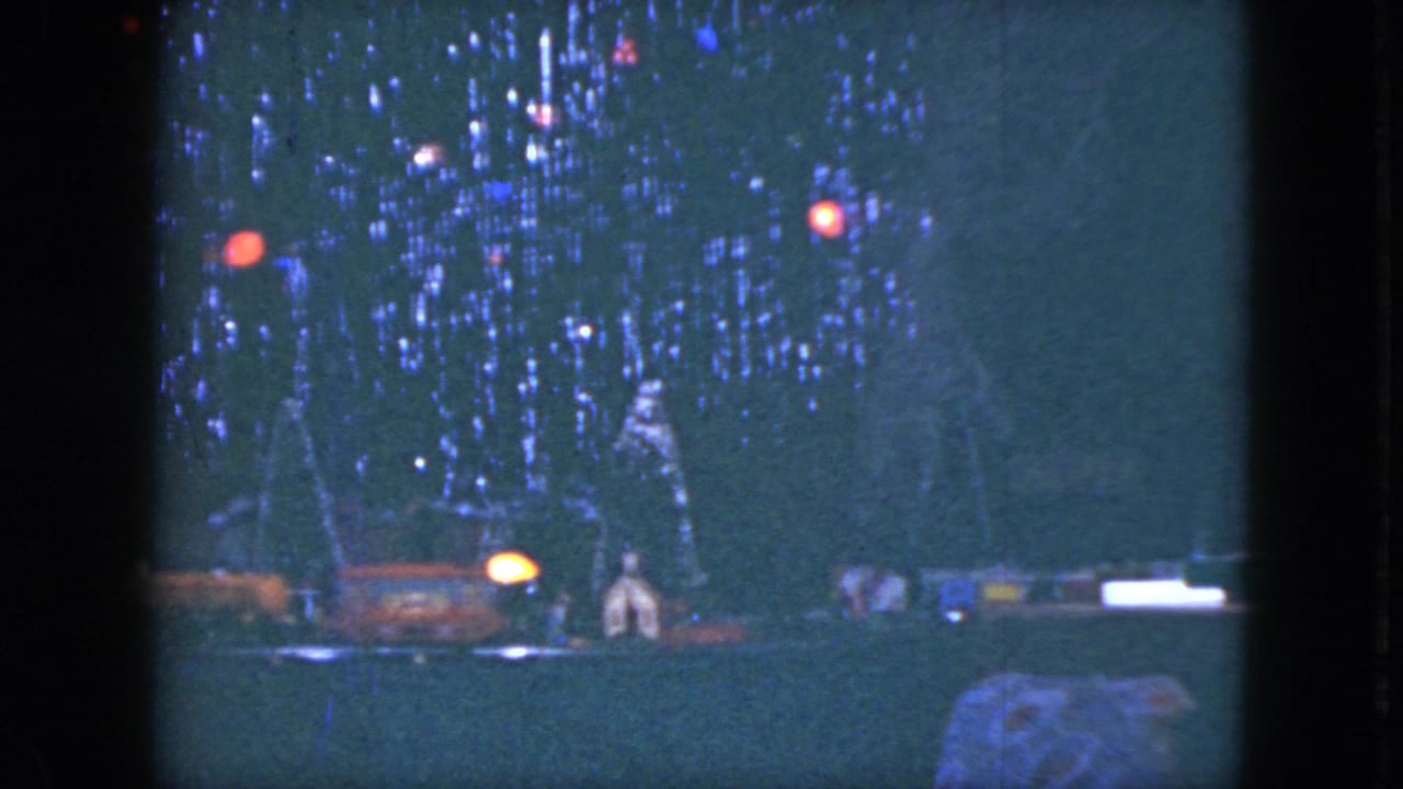 Model train display beneath a decorated Christmas tree with glowing colored lights.