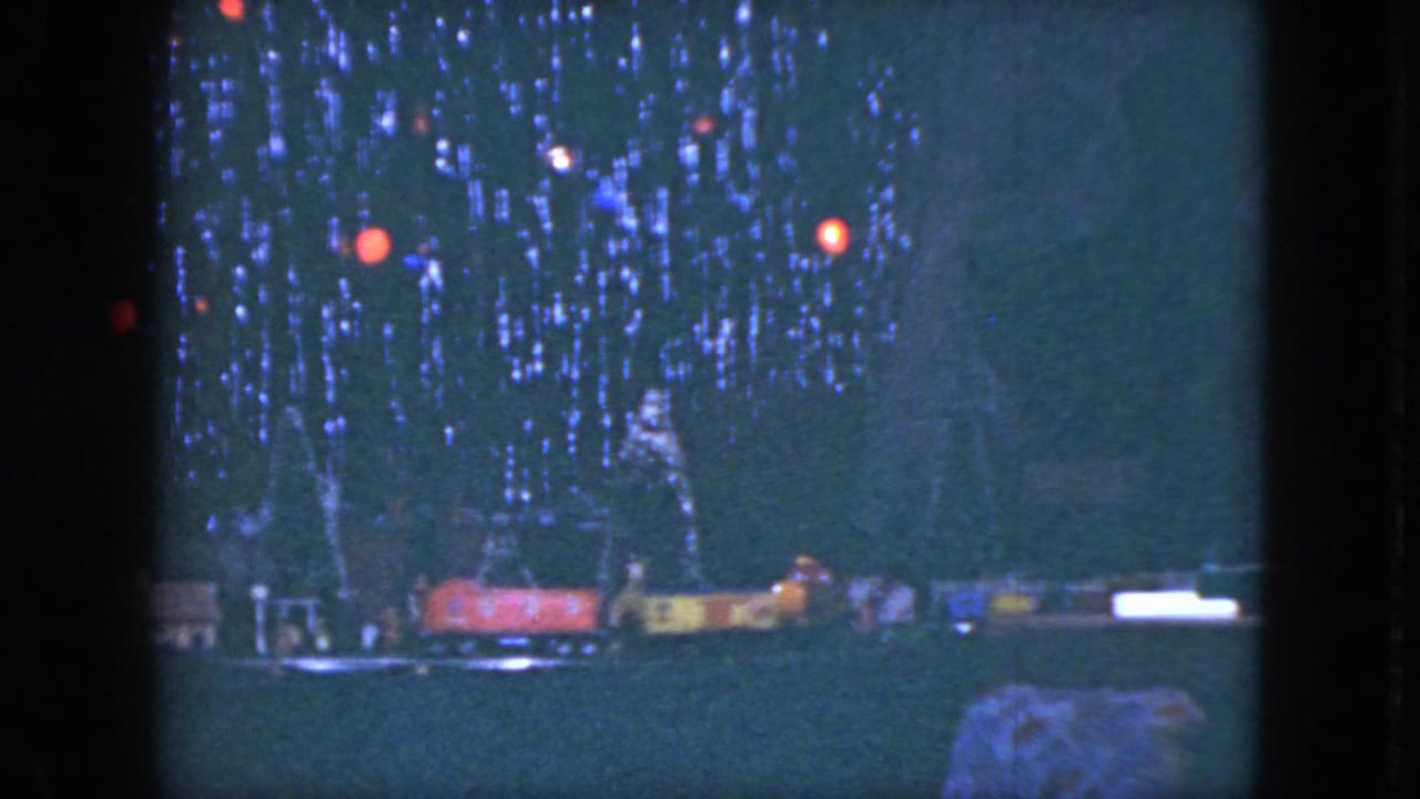 1951 Cleveland 8mm frame with colored Christmas lights over a tabletop model train display.