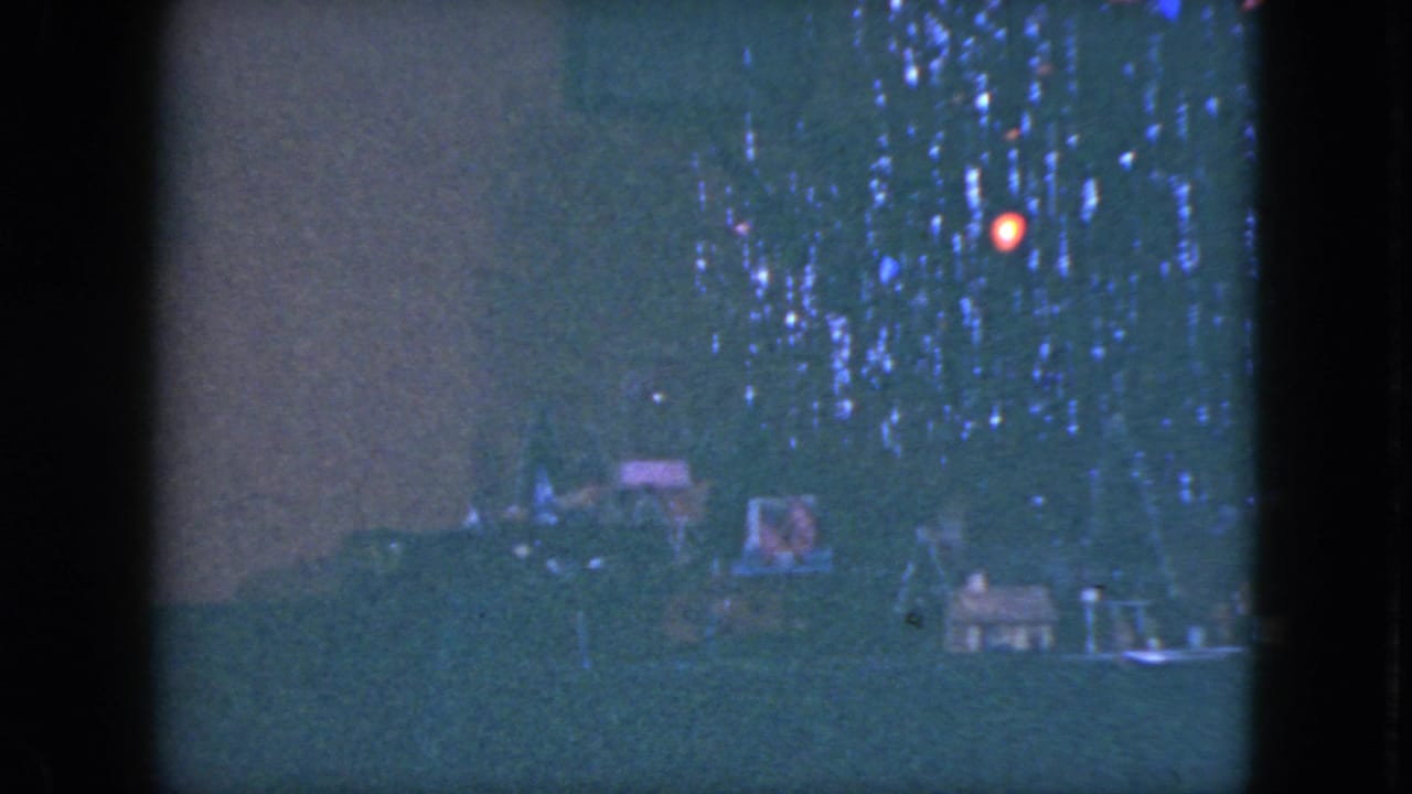 Soft 8mm frame of a Cleveland holiday interior with tree lights and a small train display, consistent with the 1951 metadata.