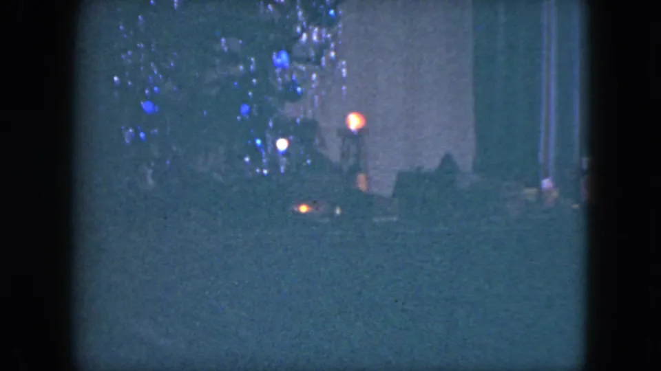 The closing frame holds on the lit Christmas tree and toy train display inside the 1951 Cleveland home-movie scene.