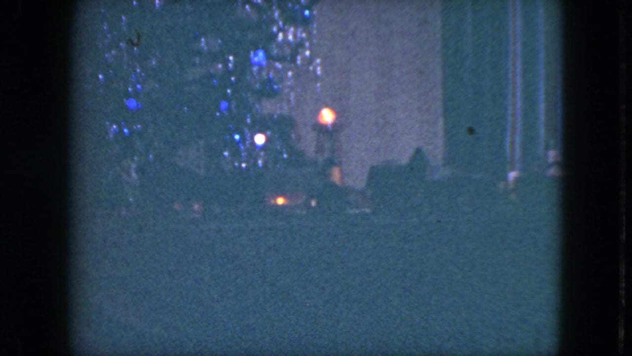 1951 Cleveland nighttime frame with blue decorative lights, a dark foreground, and a small orange vehicle-like light beyond.