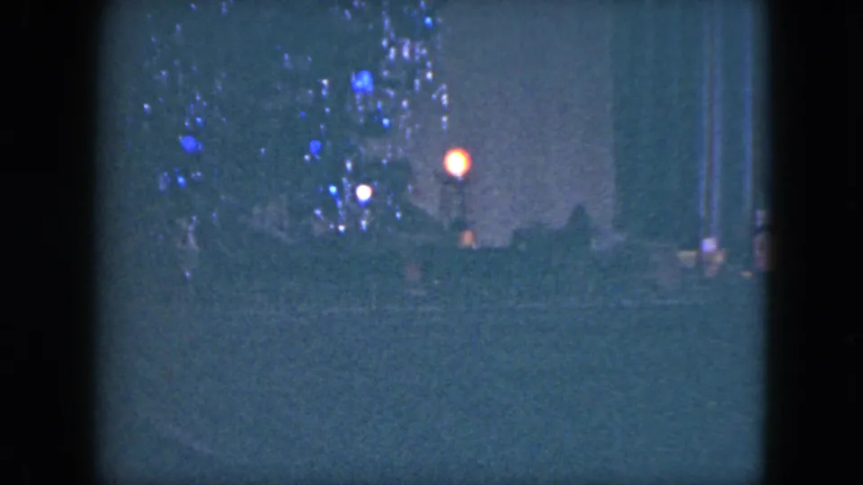 1951 Cleveland 8mm frame showing a dark miniature holiday scene with a small lit tree and warm points of light near a model railroad layout.