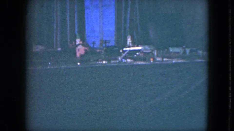 1951 Cleveland 8mm frame showing the model train passing across a miniature holiday layout, with motion blur and a blue backdrop.