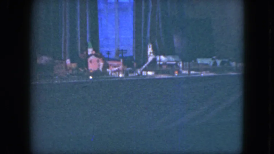 Final 1951 8mm frame holds on the miniature train display, showing small structures, tree shapes, lights, and aged blue-green film texture.