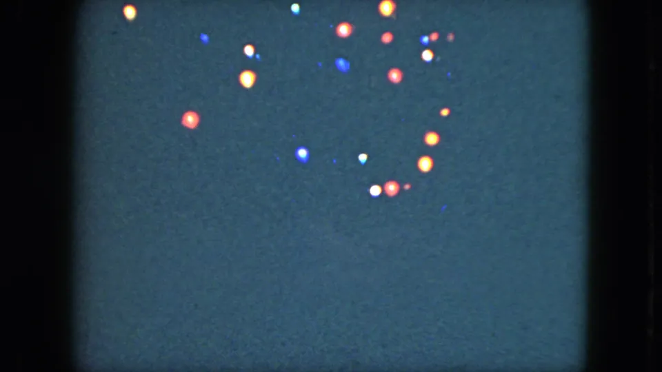 A cluster of colored holiday lights appears in soft focus on dark 8mm film from the Cleveland home-movie clip.