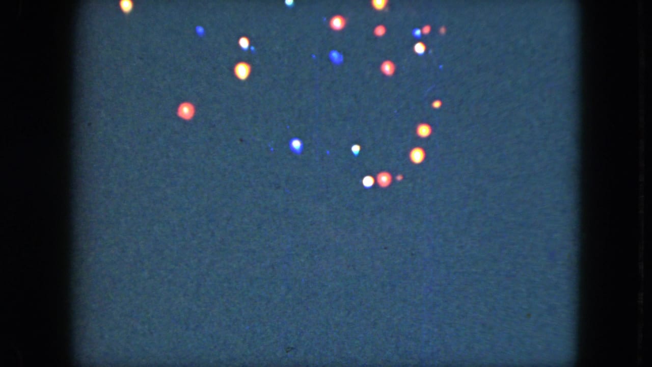 1951 Cleveland 8mm frame with red, blue, white, and amber lights clustered near the top of the night sky.