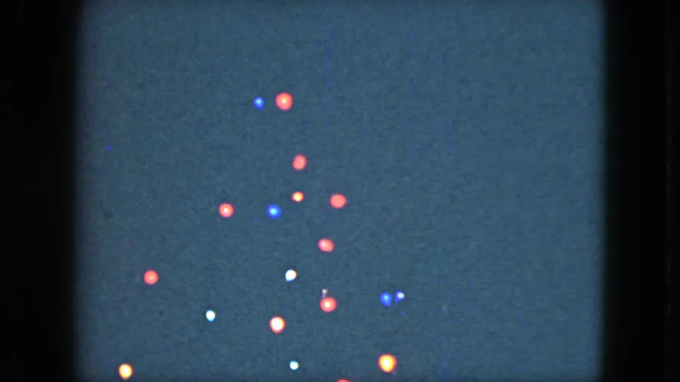 1951 Cleveland home-movie frame showing red, blue, white, and amber bulbs glowing in a loose tree-like arrangement at night.