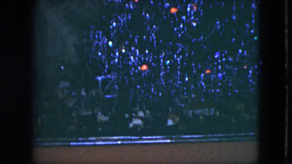 1951 Cleveland home-movie frame of a Christmas tree with blue tinsel, red ornaments, and lights seen beside a dark vertical frame.