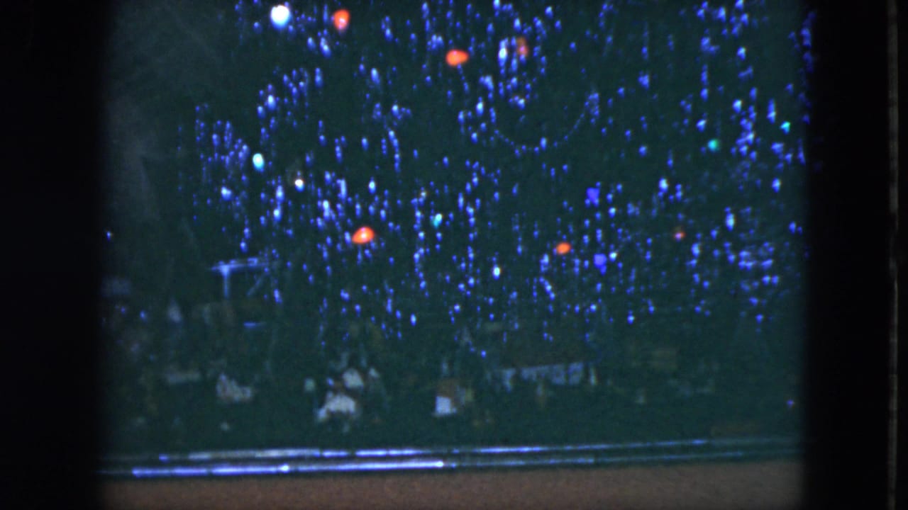 1951 Cleveland 8mm frame showing a decorated Christmas tree with blue tinsel, small lights, and a red ornament near a dark frame.