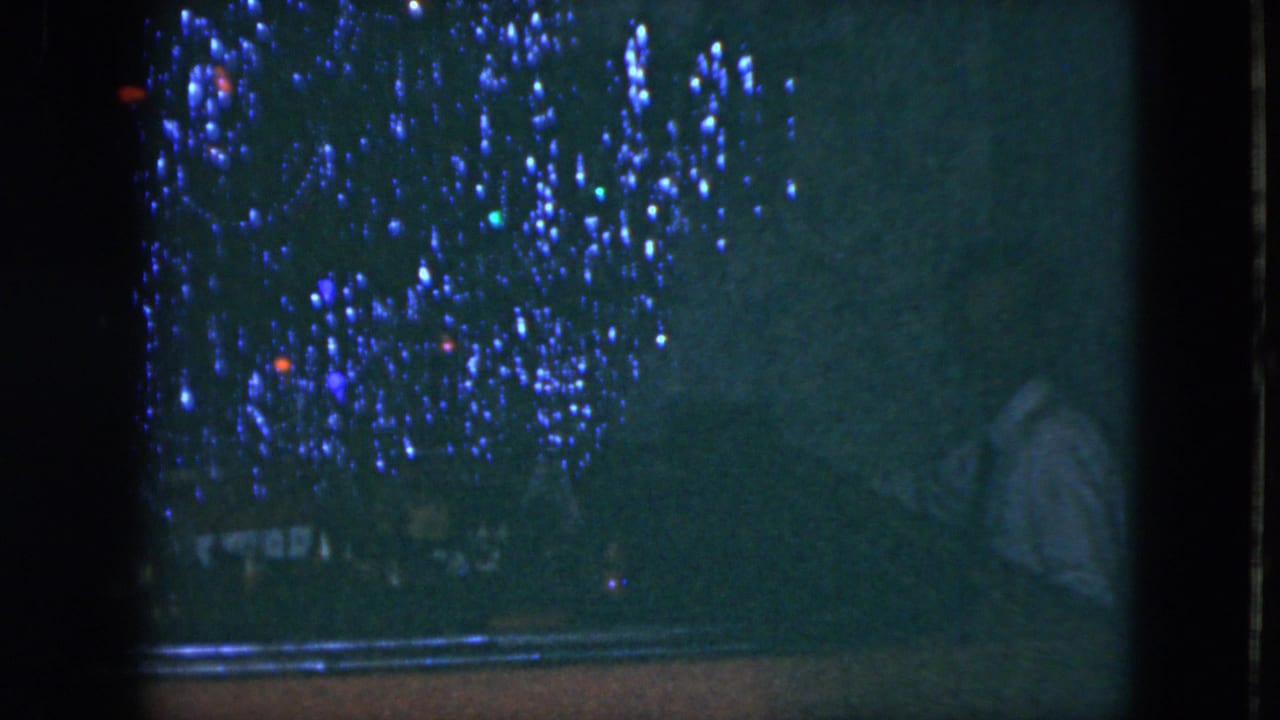 Dim piano scene with a seated figure in a white shirt amid blue and red lights.