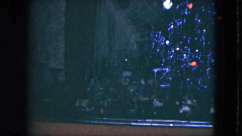 Final 1951 Cleveland frame with blue Christmas lights, red ornaments, faint lower figures, and visible 8mm film texture.