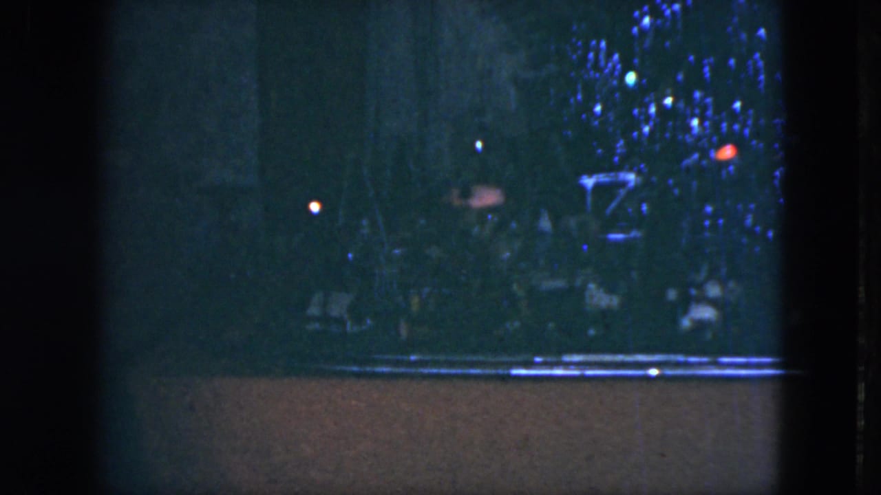 1951 Cleveland frame with a dark Christmas tree display, scattered colored bulbs, and a bright horizontal ledge or train track at the lower edge.