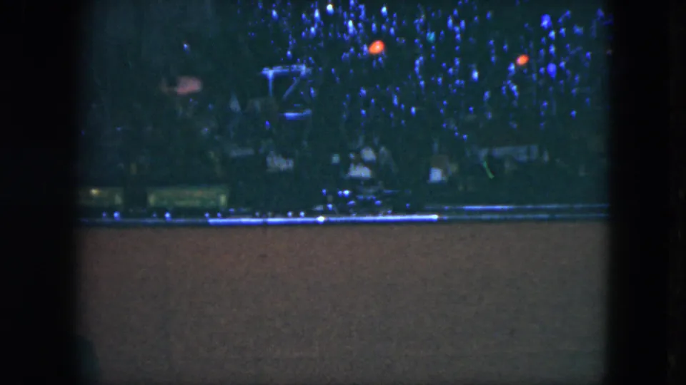 1951 Cleveland home-movie frame showing a model train running under blue and red Christmas tree lights.