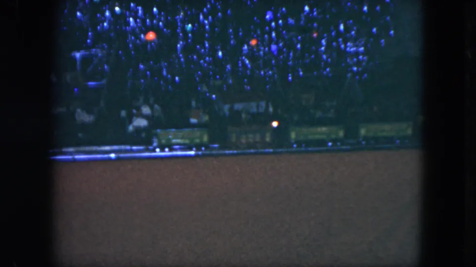 1951 Cleveland 8mm still of a model train beneath a decorated Christmas tree in low light.
