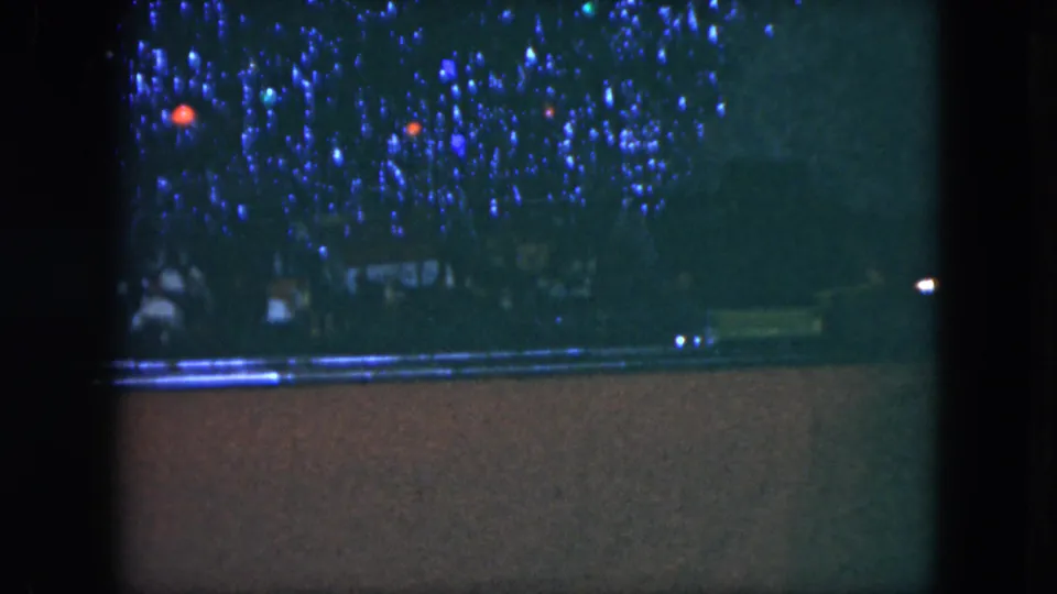 1951 Cleveland 8mm frame with a toy train layout in low light, blue decorative lights, and track visible across the lower frame.