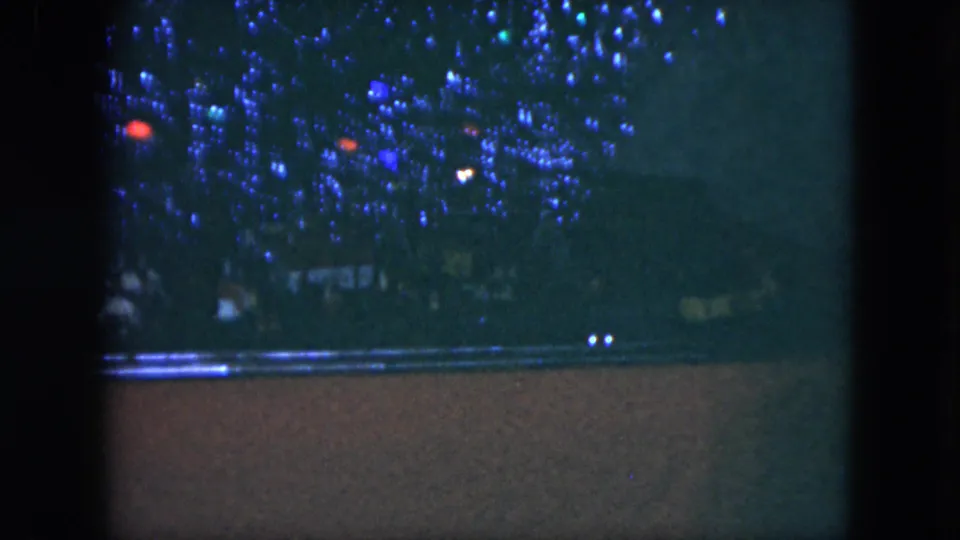 1951 Cleveland home-movie frame showing a dark crowd area with scattered blue and red holiday-style lights.