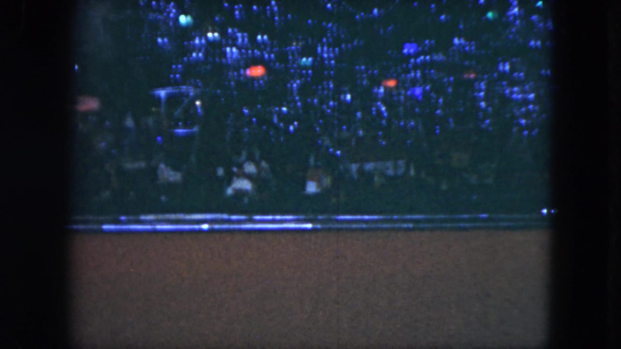 1951 Cleveland frame with a panned view of crowd silhouettes and dense blue lights, partly split by the contact-sheet border.