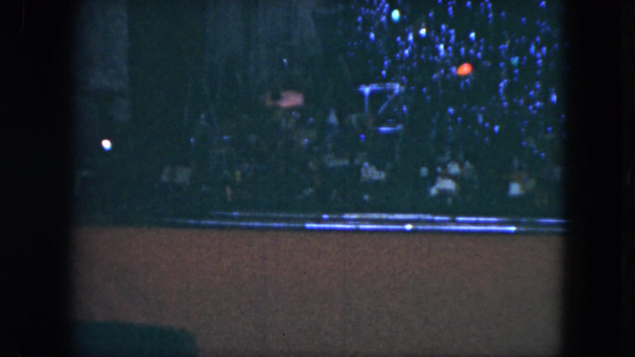 1951 Cleveland 8mm frame showing colored Christmas tree lights above a small model train track in a dim home interior.