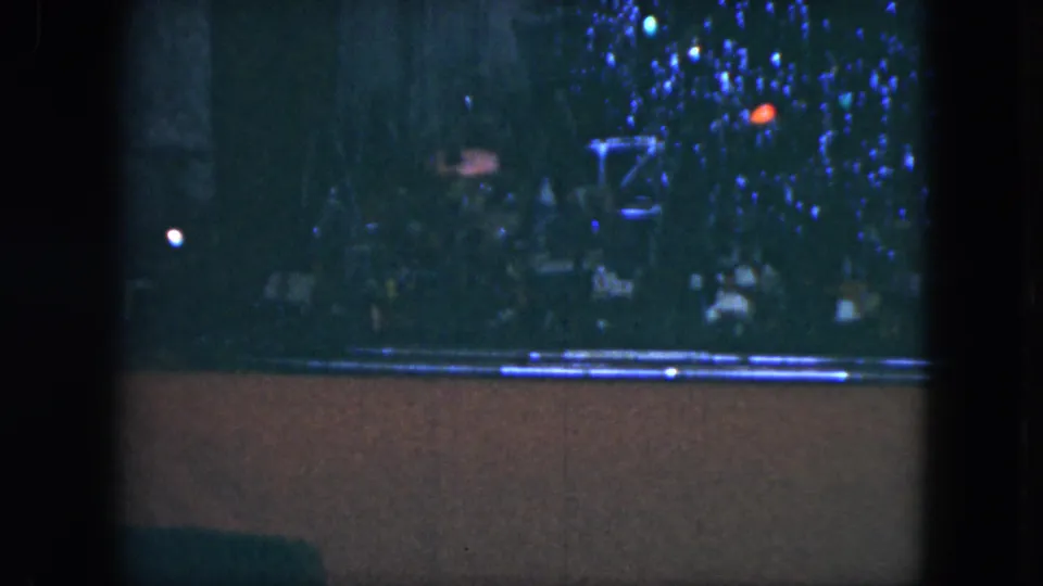 1951 Cleveland 8mm frame showing colored Christmas tree lights above a small model train track in a dim home interior.