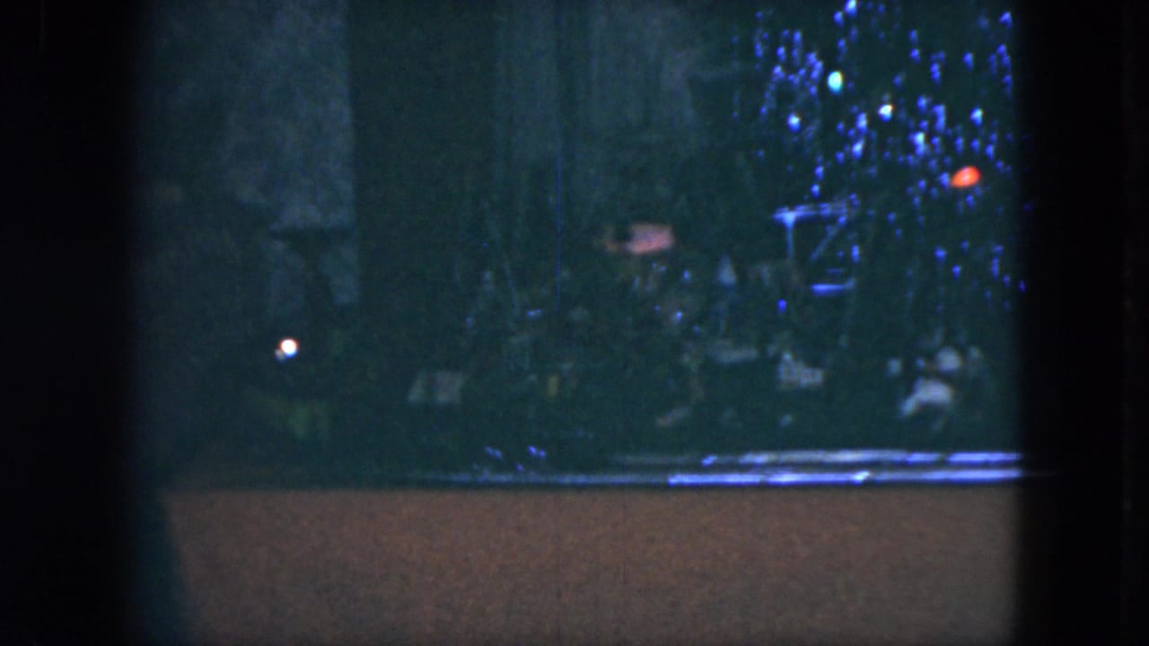 1951 Cleveland 8mm frame showing a toy train near a blue-lit Christmas tree display, partly obscured by dark vertical framing.