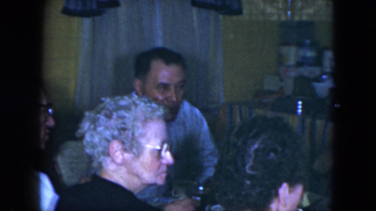 Adults seated around a kitchen table during a home gathering.