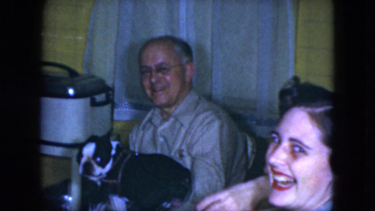 A laughing woman enters the side of the 1951 Cleveland kitchen scene while an older man sits with a black-and-white dog.