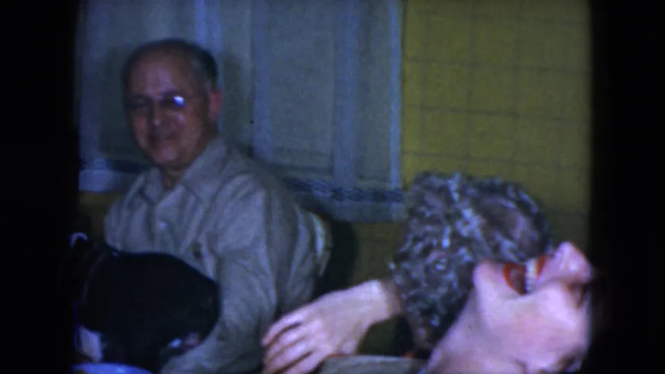 The final frame shows the older man smiling as two women sit nearby in the 1951 Cleveland kitchen home-movie scene.