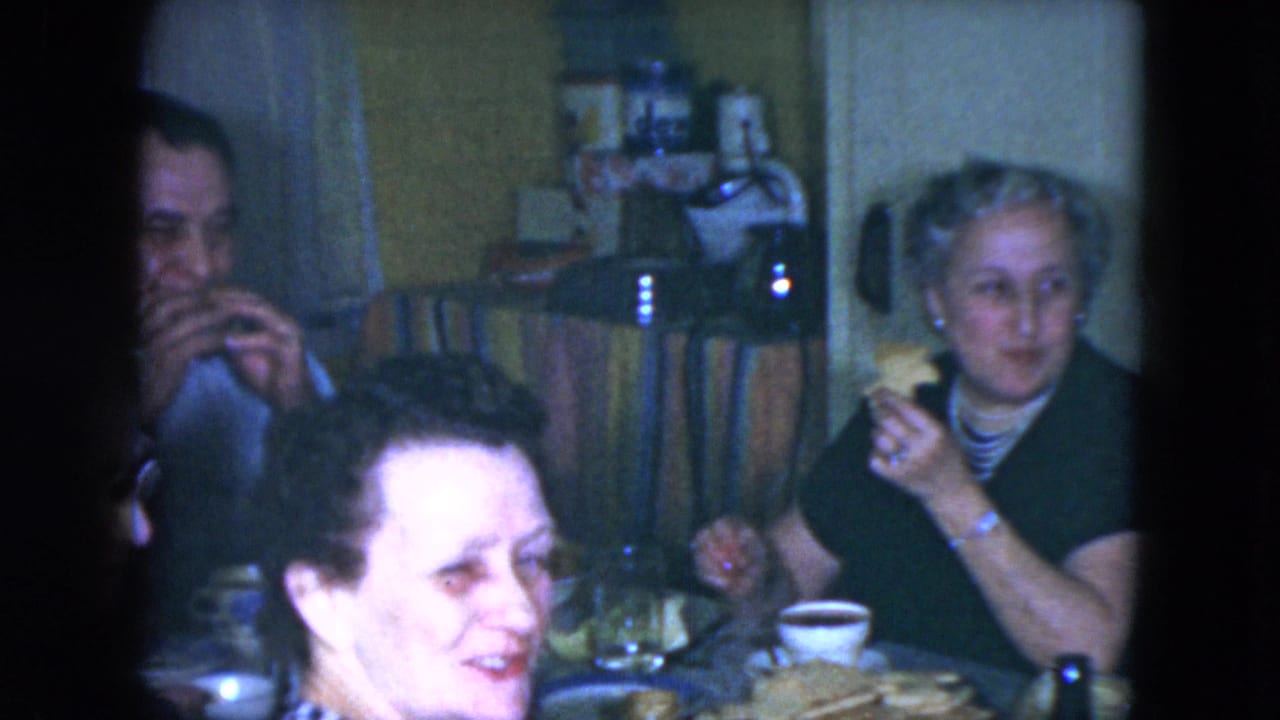 Adults seated at a dining table with food and cups in a private room.
