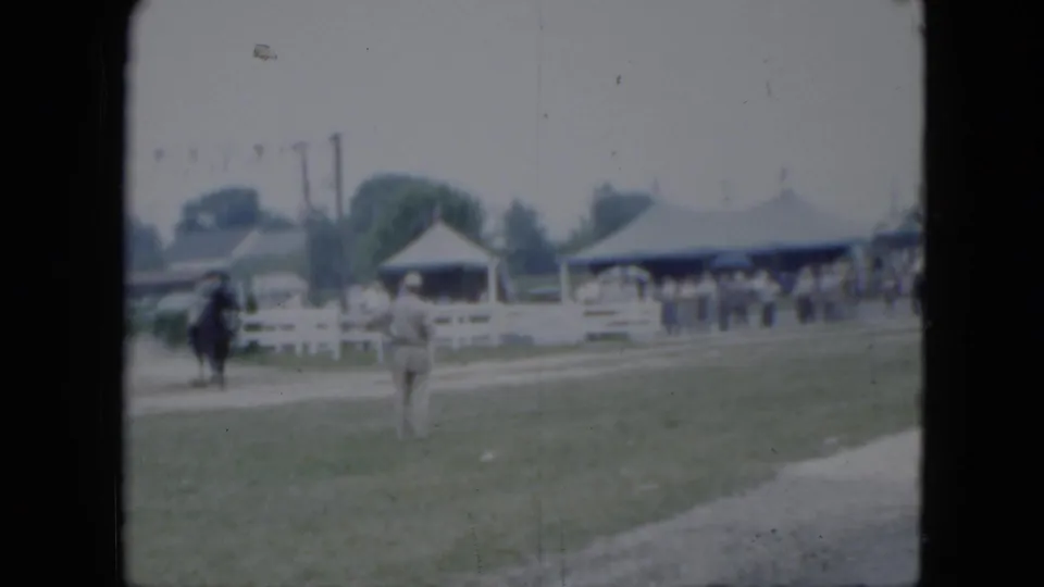 1951 Cleveland fairground view with a horseback rider, white rail fencing, tents, and spectators in the background.