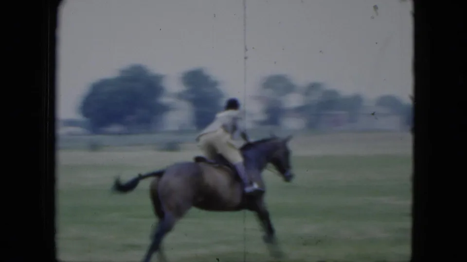 A closer 1951 Cleveland frame shows the rider leaning forward on a dark horse crossing the fairground grass.