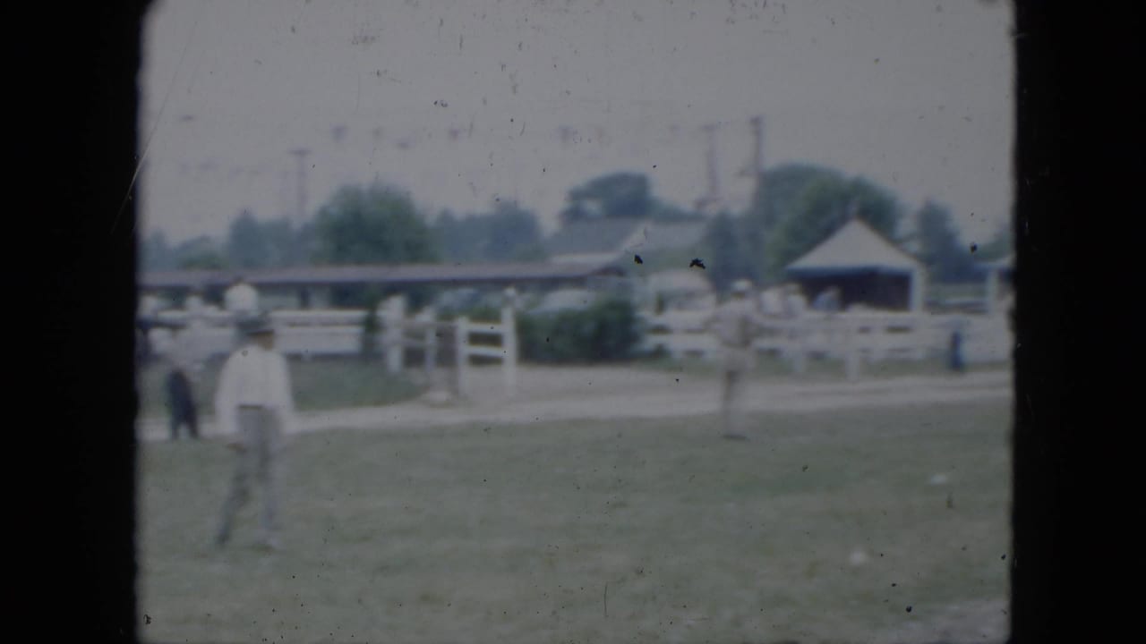 A man crosses the open field at a Cleveland equestrian setting, with white fencing, tents, and visitors in the background.