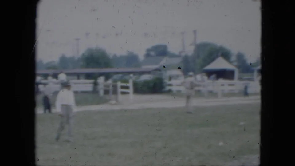 A man crosses the open field at a Cleveland equestrian setting, with white fencing, tents, and visitors in the background.