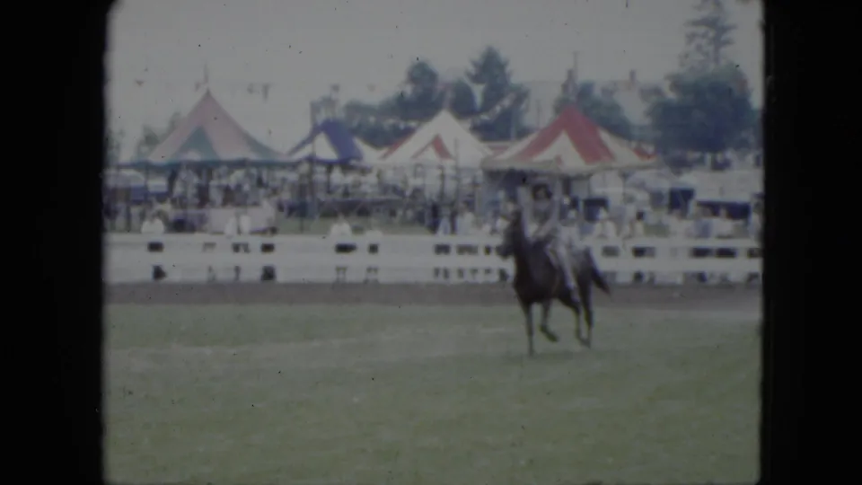 A rider on a dark horse appears near center frame at the 1951 Cleveland fairground horse show, backed by striped tents and a spectator line.